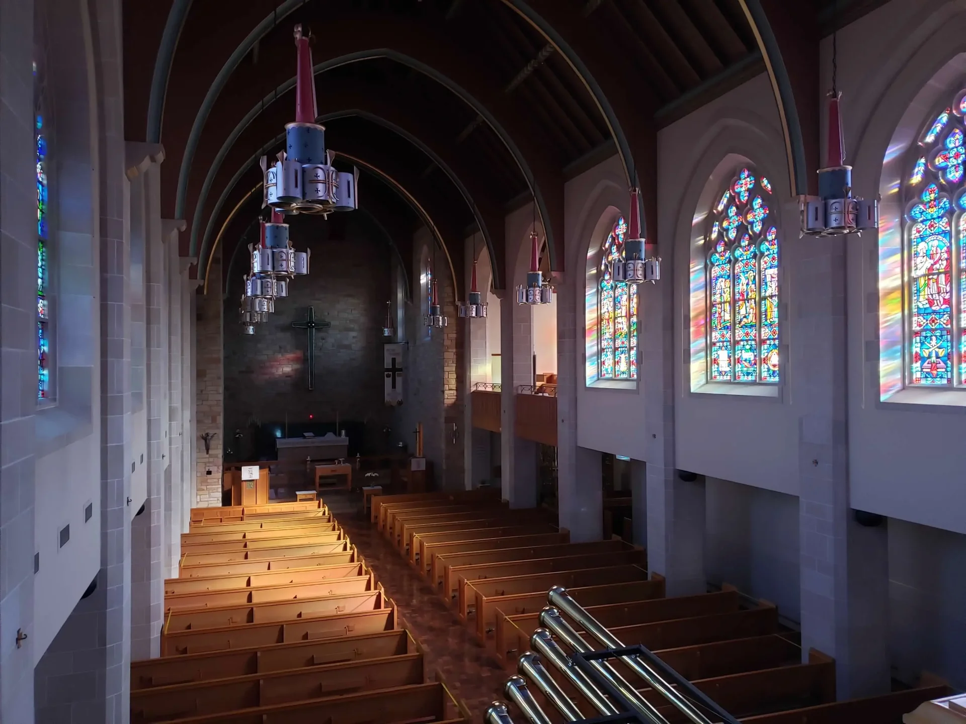 Zion Lutheran Church's nave and pews seen from the balcony, with stained-glass windows and the chancel cross