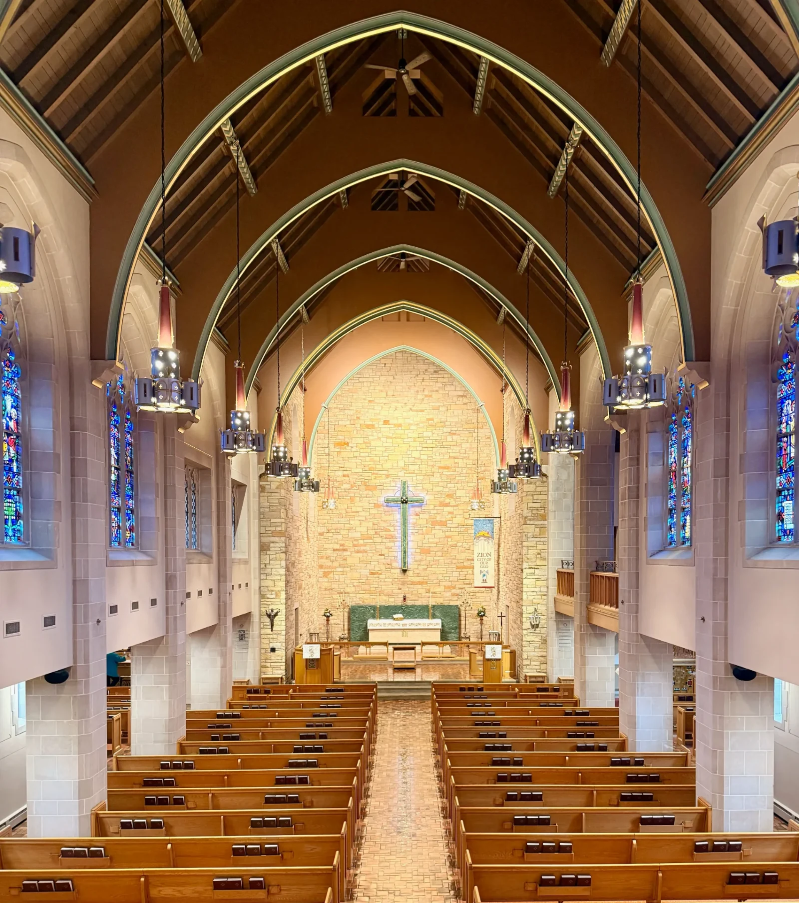 The nave and chancel of Zion Lutheran Church, Wausau, with its arched ceiling, stained-glass windows, and the cross above the altar